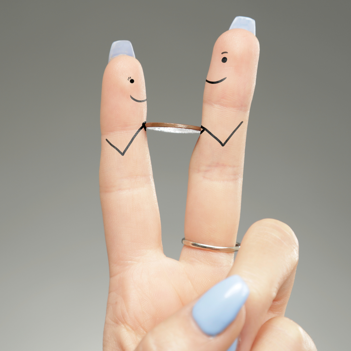 Deux doigts d'une main sur lesquels sont dessinés des visages souriants, réunis par une petite alliance.